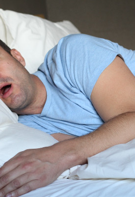 Man in light blue t-shirt in bed snoring