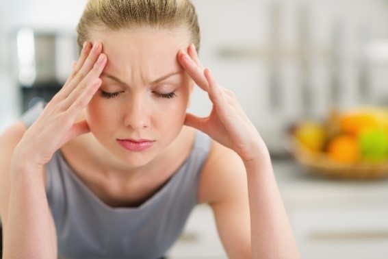 Woman experiencing a migraine headache due to TMJ disorder.
