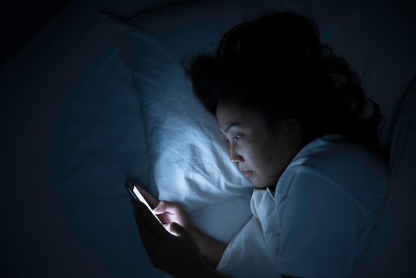 woman in bed on phone at night