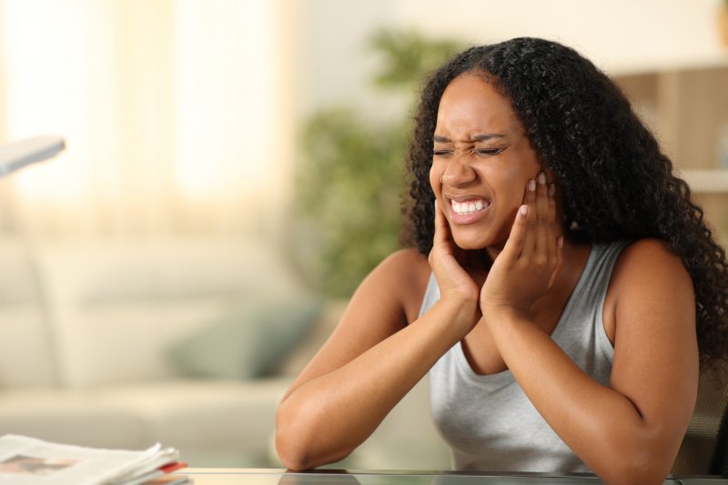 A woman holding her jaw as she suffers from a TMD-induced migraine