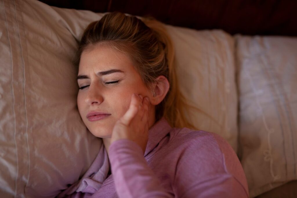 A woman struggling to sleep with jaw pain
