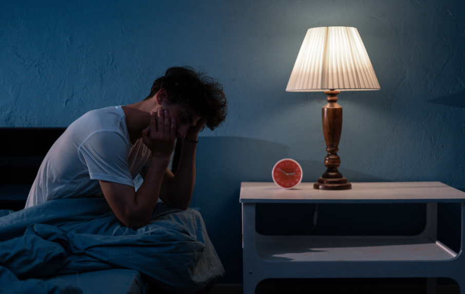 Man sitting up in bed, looking disheveled